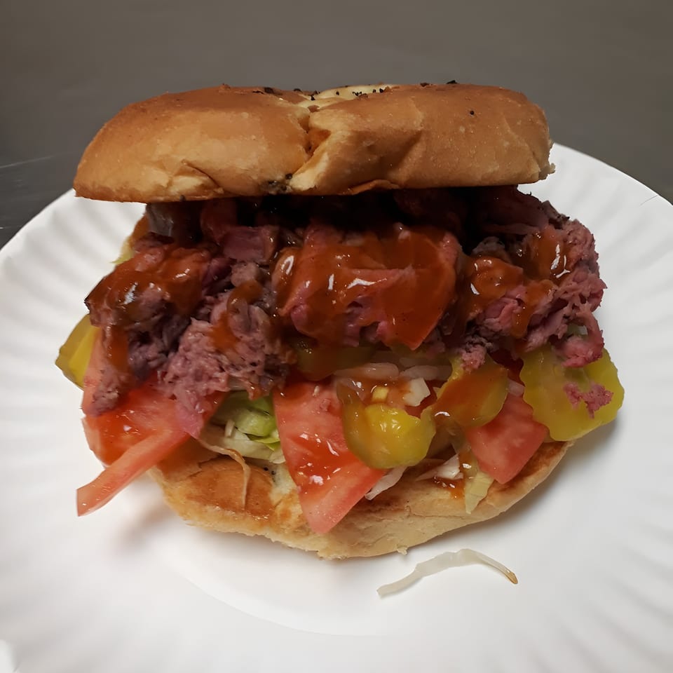 Giovanni's Roast Beef sandwich with roast beef, tomatoes, pickles, onions, and sauce on a bun.