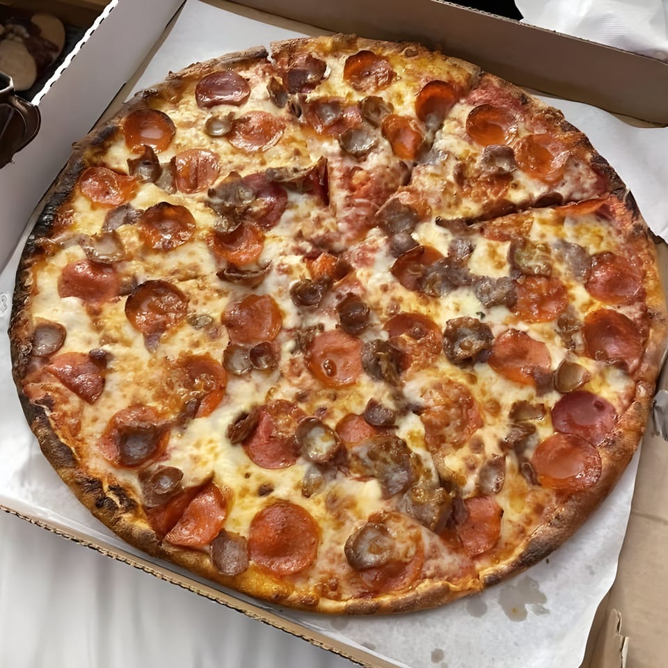 A whole Giovanni's pepperoni and sausage pizza, with one slice removed, in a cardboard box.