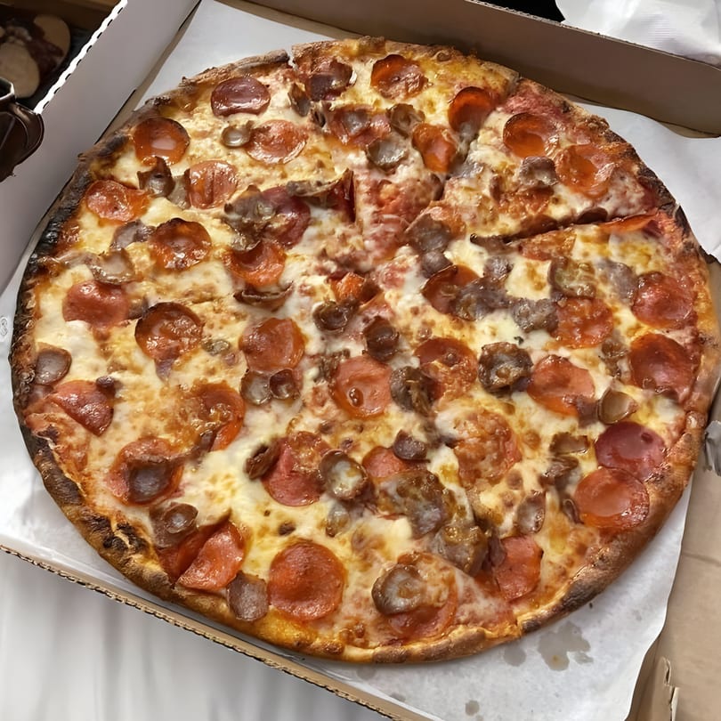 A whole Giovanni's pepperoni and sausage pizza, with one slice removed, in a cardboard box.